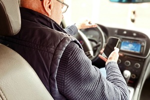 Mężczyzna trzyma telefon w ręku podczas kierowania samochodem