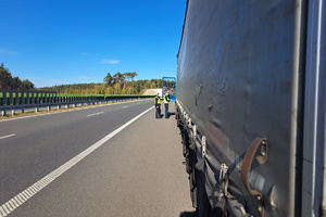 Na zdjęciu cała długość ciężarówki, z dala funkcjonariusze podchodzący do kierowcy
