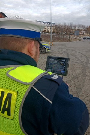 Policjant za pomocą monitora drona obserwuje zachowania kierowców