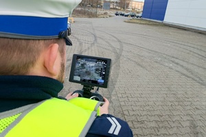 Policjant obserwuje zachowania kierowców w monitorze policyjnego drona