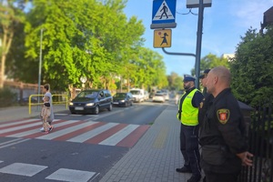 Funkcjonariusze przyglądają się pieszym na jezdni