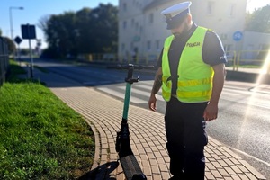Policjant ruchu drogowego stoi przy hulajnodze