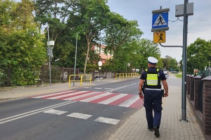 Policjant kontroluje oznakowanie przy placówkach oświatowych