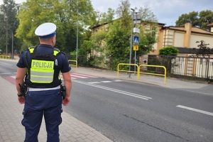 Policjant kontroluje oznakowanie przy placówkach oświatowych