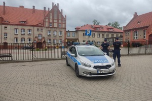 Policjant kontroluje oznakowanie przy placówkach oświatowych