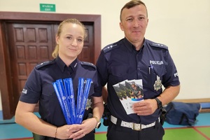 Policjanci prowadzący spotkanie z młodzieżą na sali gimnastycznej szkoły podstawowej, na zdjęciach dzieci z hulajnogami i kaskami ochronnymi