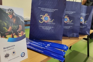 Policjanci prowadzący spotkanie z młodzieżą na sali gimnastycznej szkoły podstawowej, na zdjęciach dzieci z hulajnogami i kaskami ochronnymi