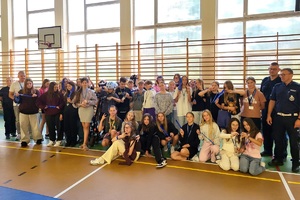 Policjanci prowadzący spotkanie z młodzieżą na sali gimnastycznej szkoły podstawowej, na zdjęciach dzieci z hulajnogami i kaskami ochronnymi