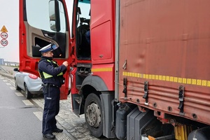 Policjant kontrolujący kierowcę ciężarówki i obserwujący ruch pojazdów dronem