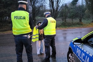 Policjanci ruchu drogowego wręczają kamizelkę odblaskową dziecku