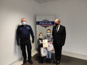 Komendant Powiatowy Policji w Tucholi oraz Wójt Gminy Kęsowo pozują z dziećmi do pamiątkowego zdjęcia