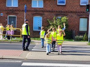 policjant omawia dzieciom zasady bezpieczeństwa na drodze
