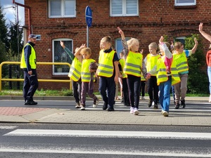 policjant omawia dzieciom zasady bezpieczeństwa na drodze